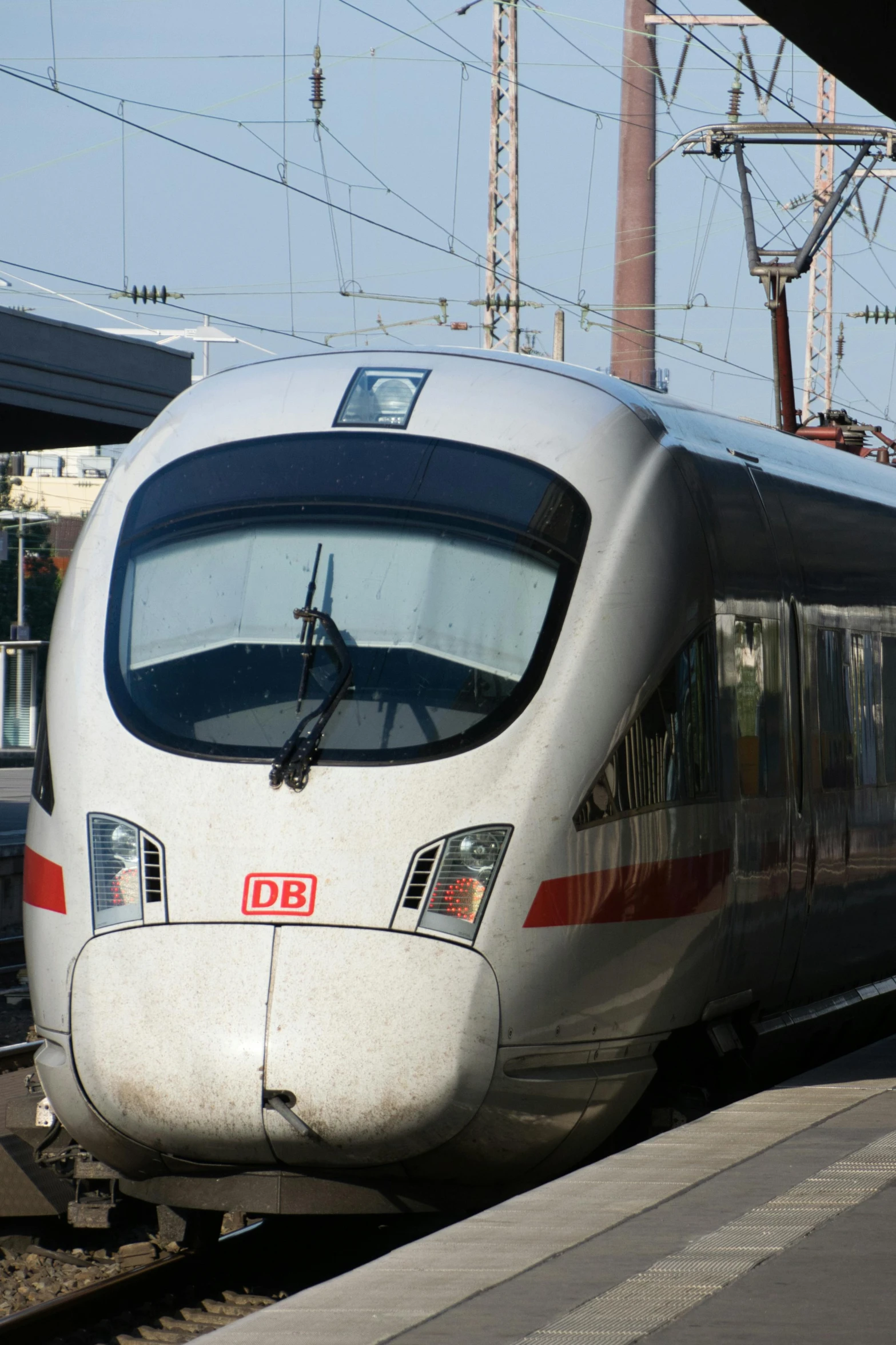 a silver bullet train pulling into a train station