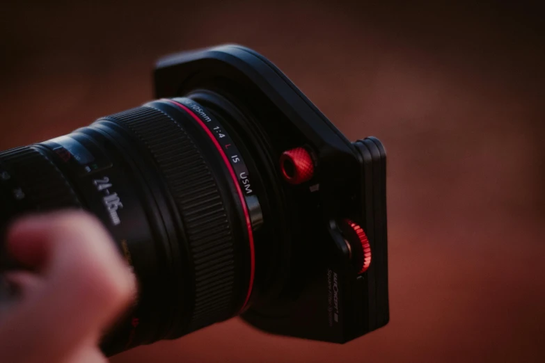 a person's hand holding a camera over the lens