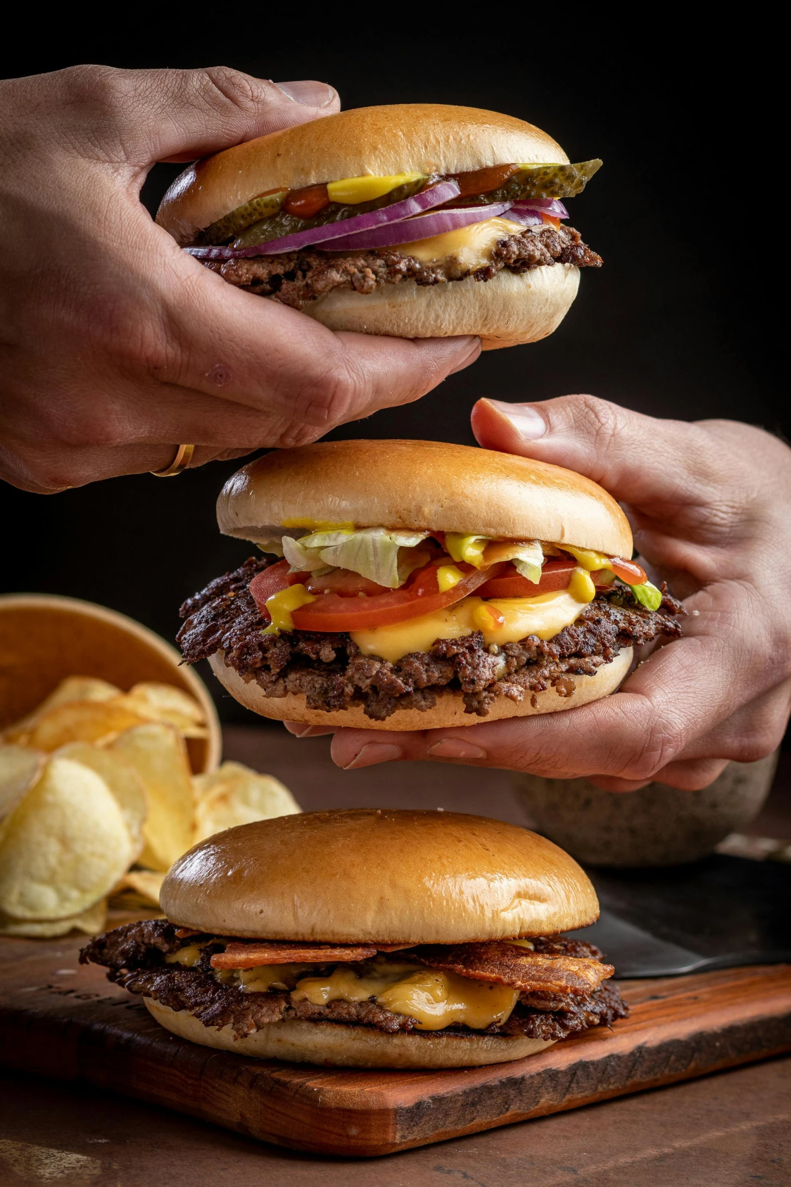 three people grabbing a large hamburger into each others hands