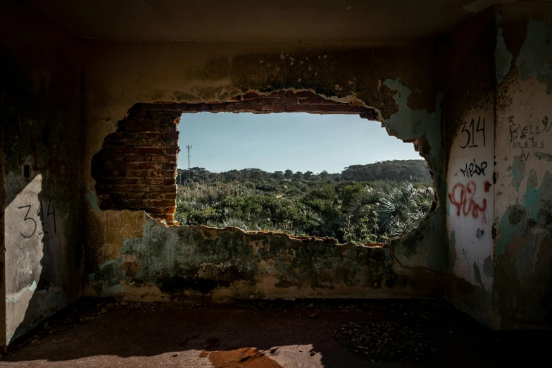 an old window is seen through a wall that has graffiti on it