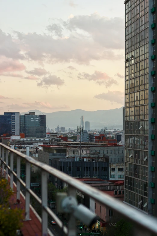 a metal hand rail overlooks a city and mountains