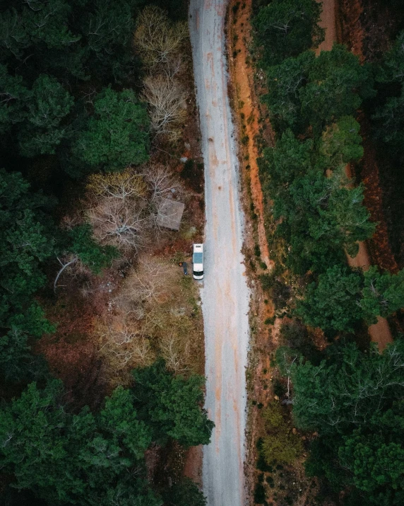 an aerial view of an empty dirt road and some forest