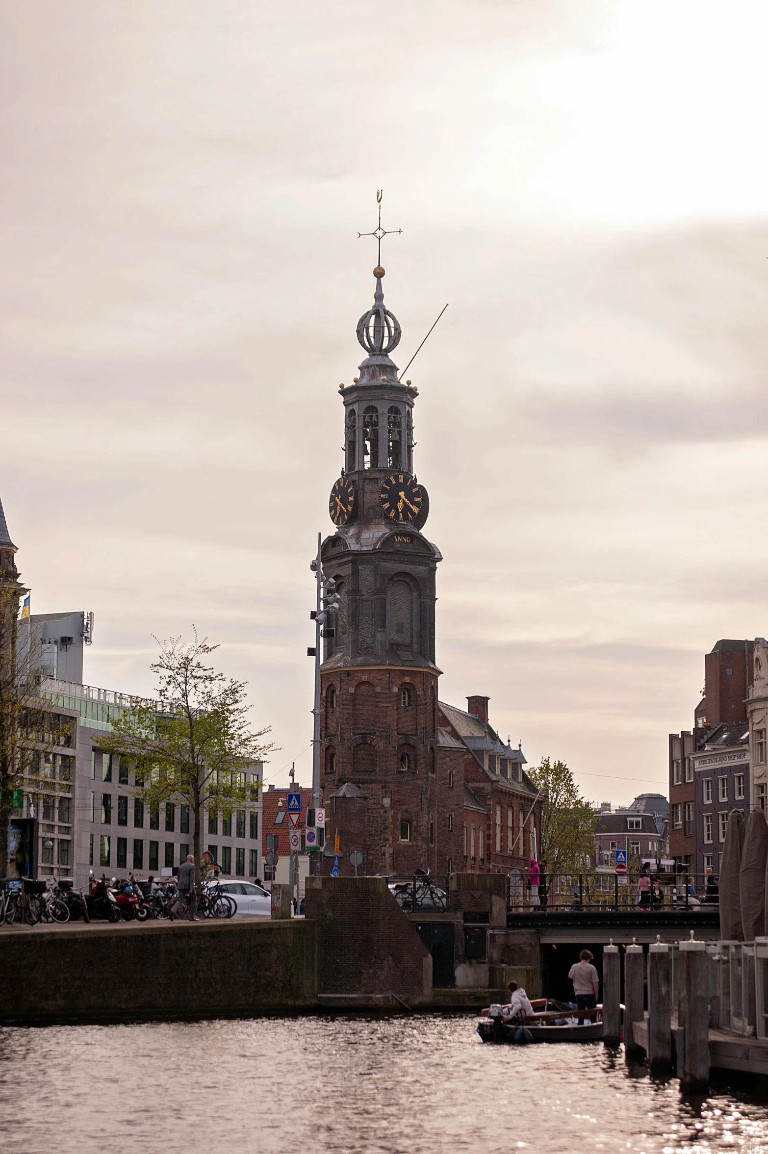 a boat sailing down a canal near a tall tower