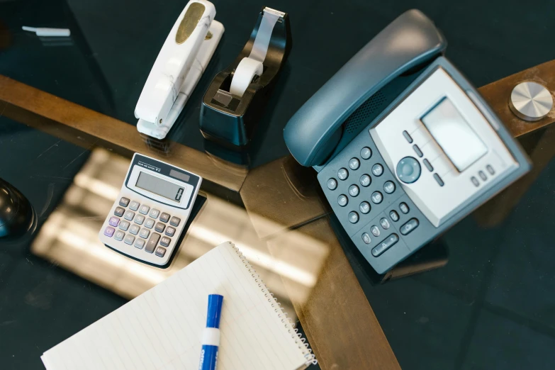 an office desk with a rotary office phone and tape dispenser