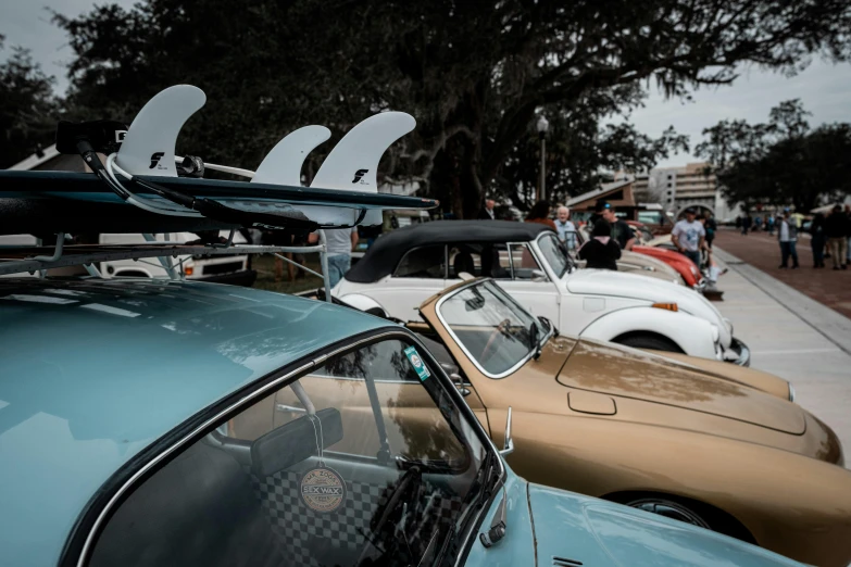 a number of cars on a street with surf boards mounted to their roof