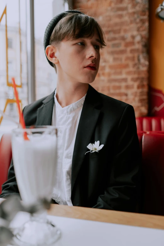 a young man wearing a suit sitting at a table