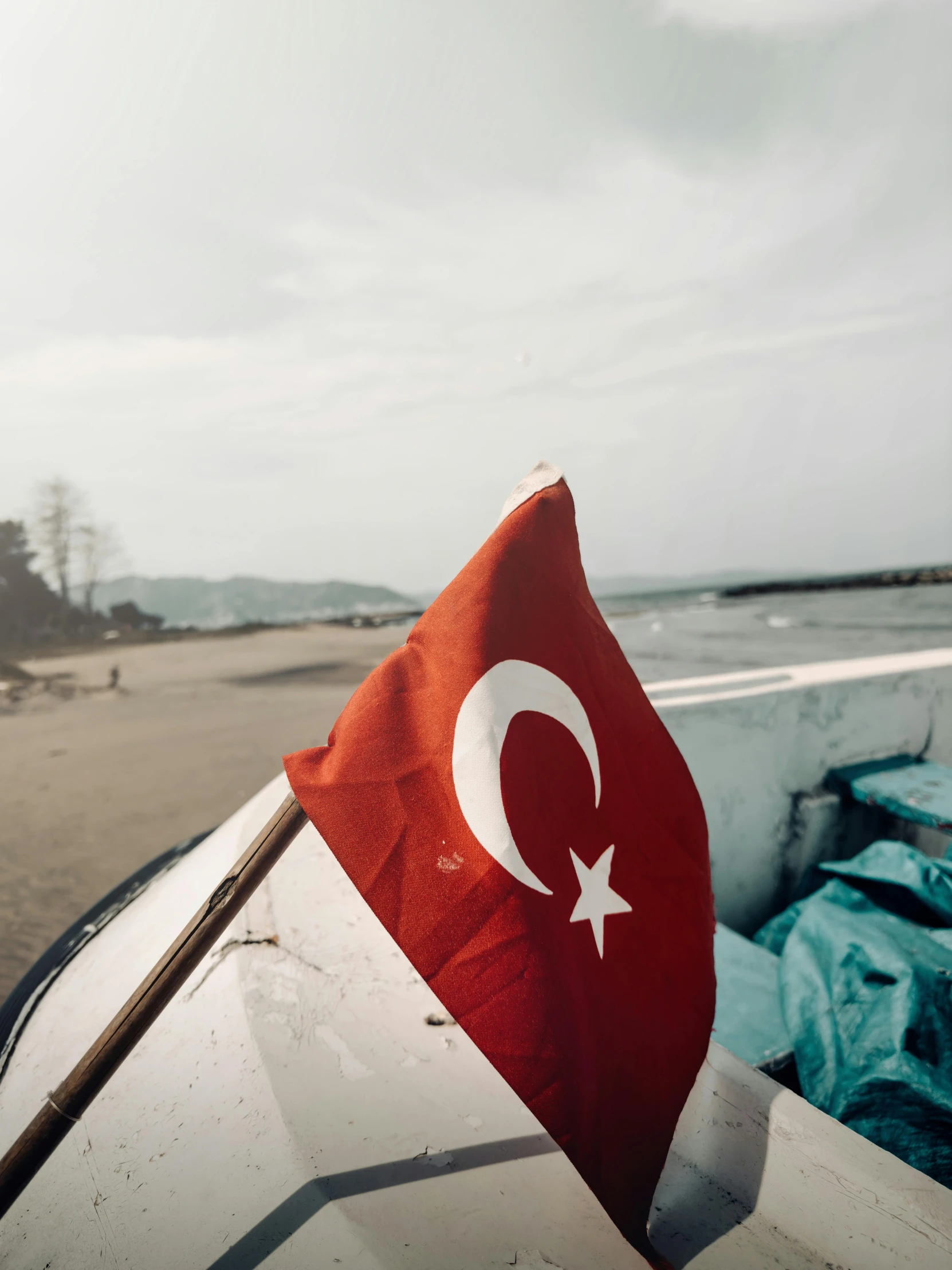 a red flag on the top of an old white boat on the beach