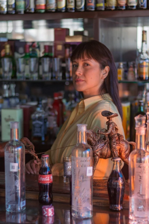 a woman sitting behind a bar that has bottles on the counter