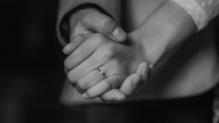 couple holding hands and putting on a wedding ring
