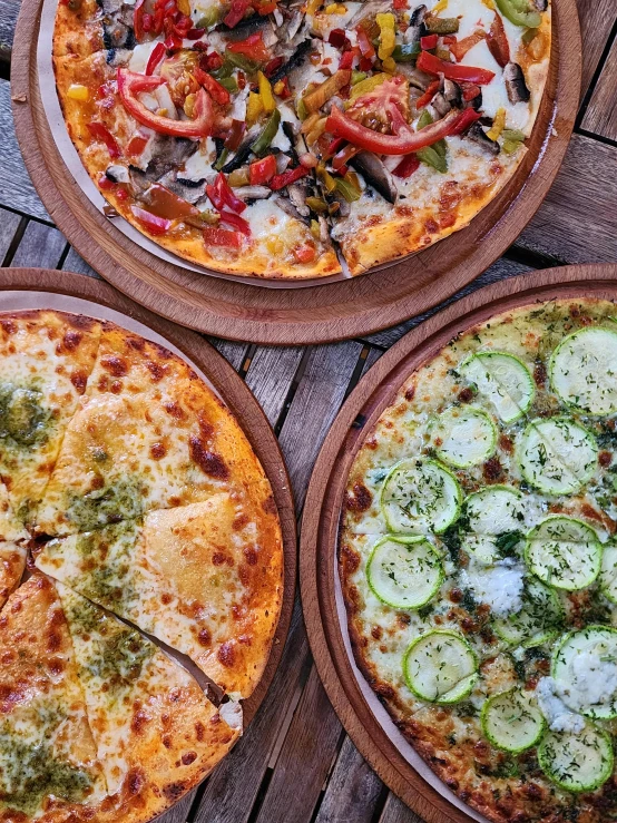 three different pizzas sitting on a table