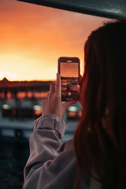 a woman takes a po of an orange sky