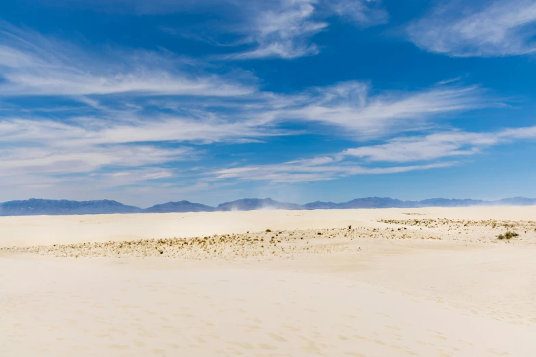 there is an empty beach and mountain behind the sand