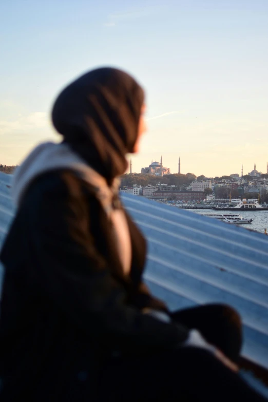 a woman looks over the top of a rooftop towards a river