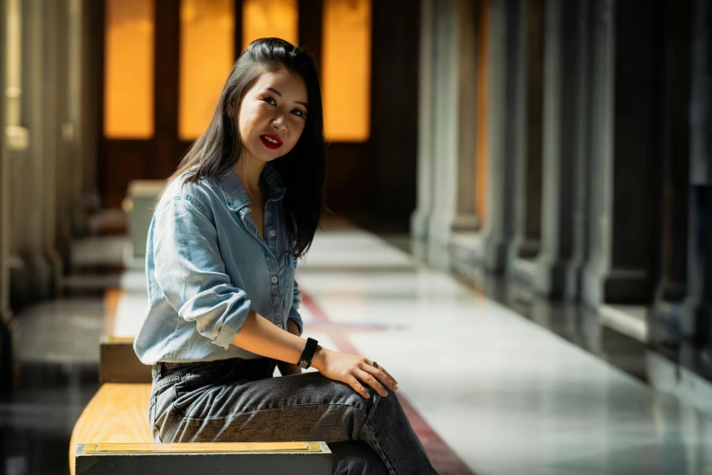 a woman sitting on top of a wooden bench in an airport