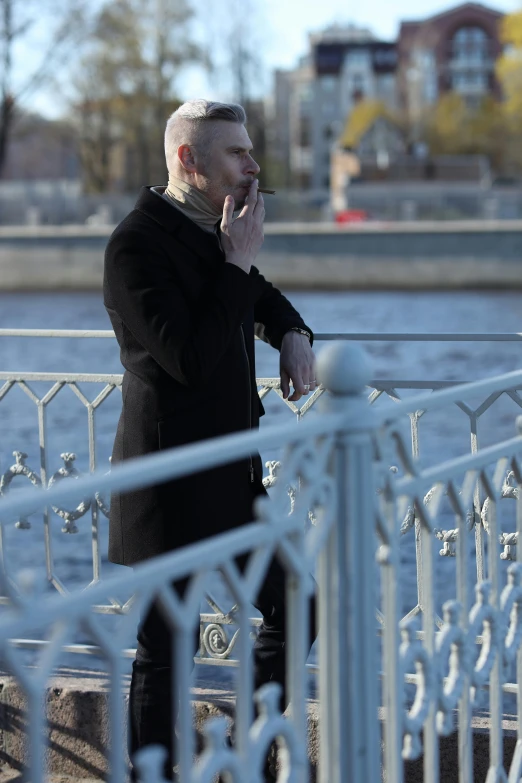 a man in a black suit with white hair on the bridge