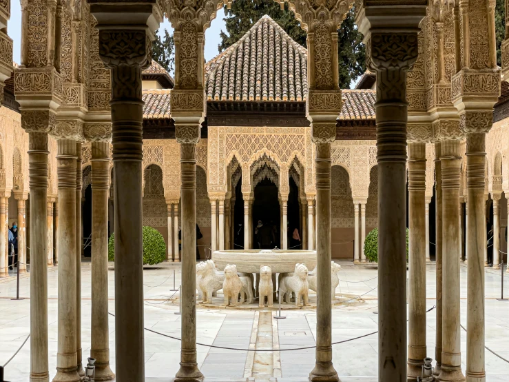 a stone building with an ornate archway, sitting at the front and two marble benches set on either side of the walkway