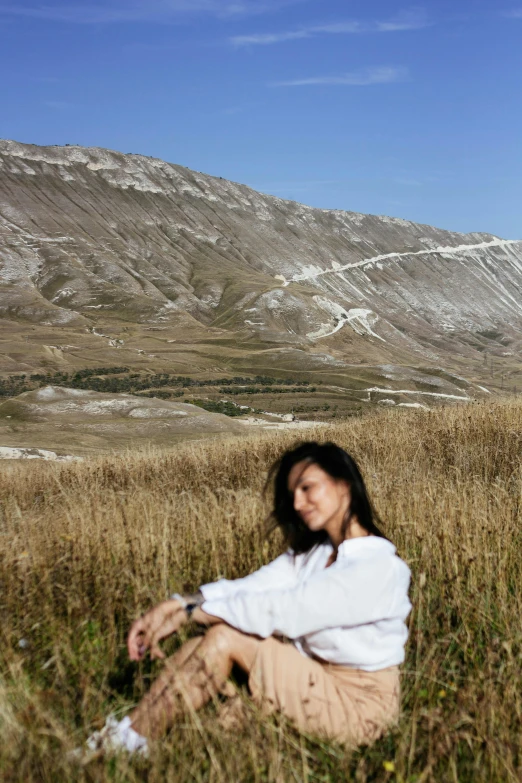 an asian woman is sitting down in the grass