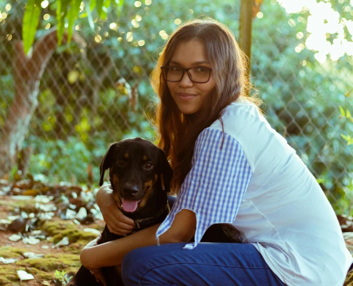 a girl with glasses and glasses is kneeling next to a dog