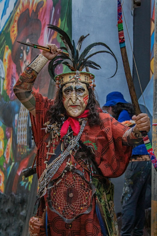 a man in a costume holds two sticks in his hands