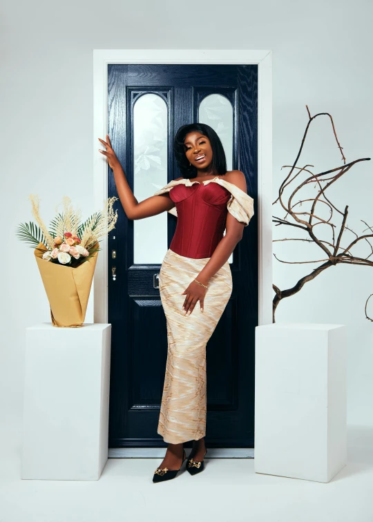 a woman posing outside of a door in front of plants