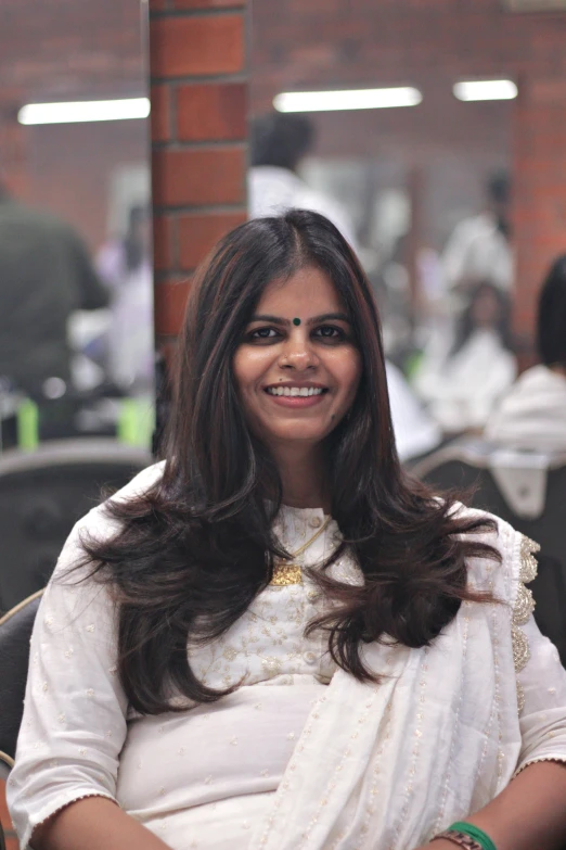 an indian woman smiles and sits in a chair