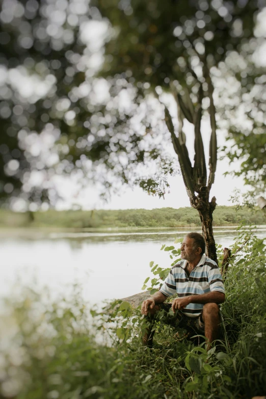 a man sits in front of a river by himself