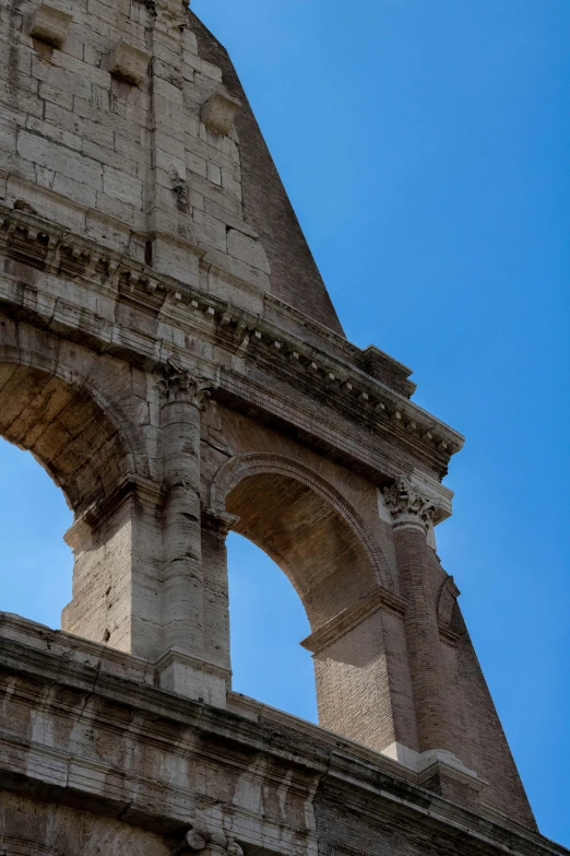an arch of an ancient roman structure is in the clear blue sky