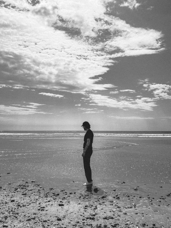 black and white pograph of a man standing on beach