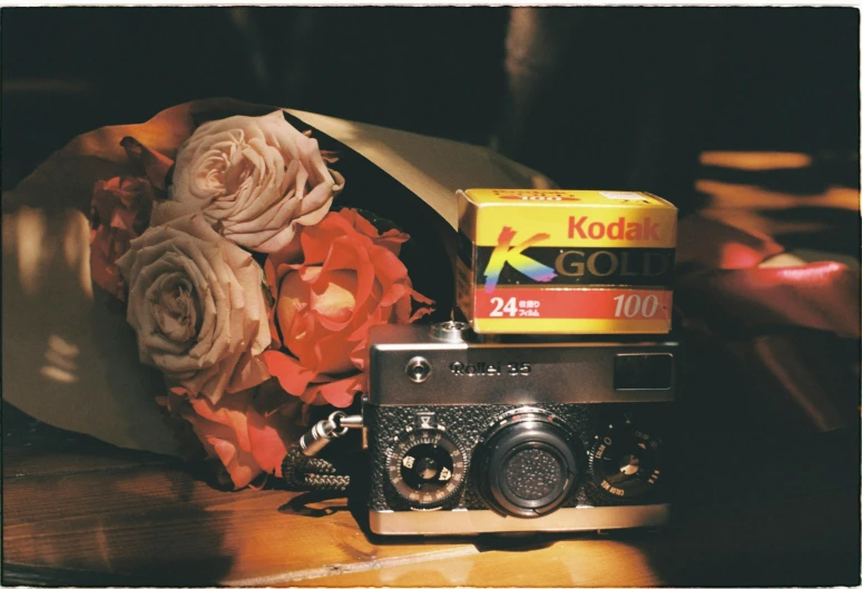 a camera next to flowers, an old fashioned box and a box of kodak instant film