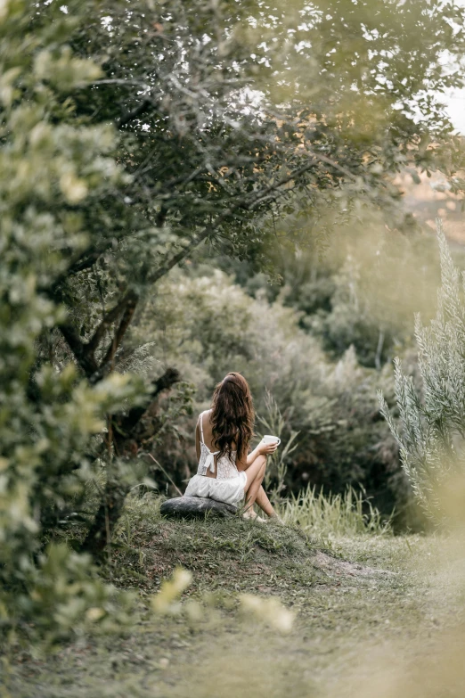 woman with long hair sitting in grass looking at the sky