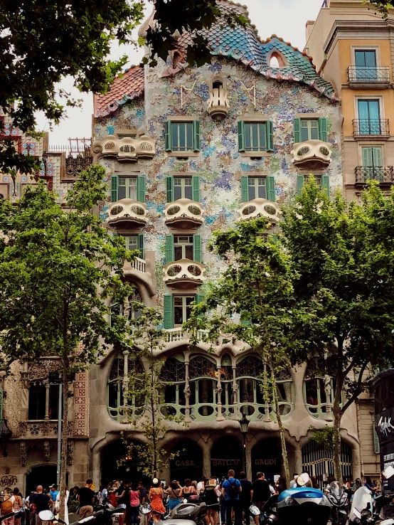 many people standing near a building that has a multi - colored mosaic roof