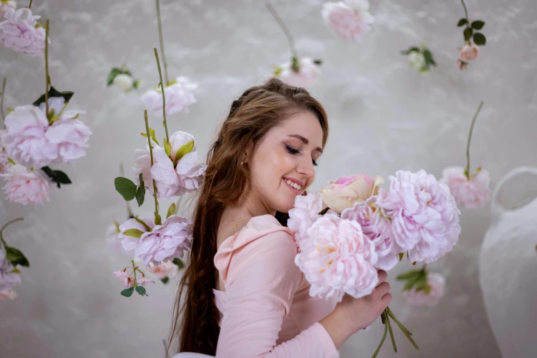 a girl holding some pink flowers smiling at soing