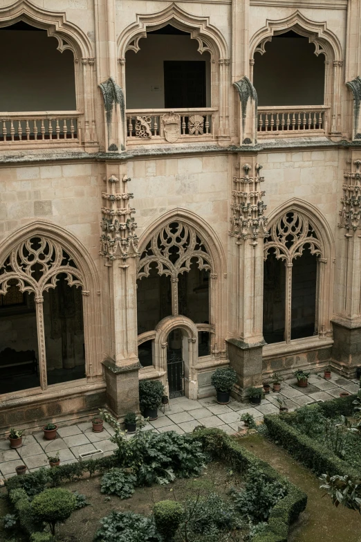 a building with a very ornate balcony and lots of flowers in the courtyard