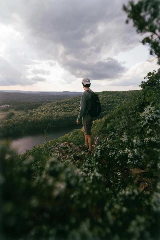 a person stands atop a hill next to a river