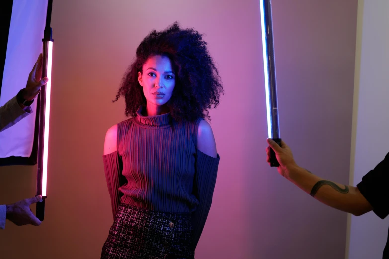 a young woman holding up two lights sticks in a room