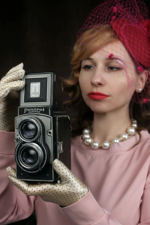 the woman is holding up an old camera