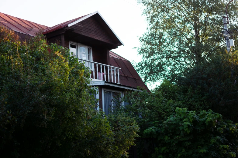 a house with a red tin roof and balcony