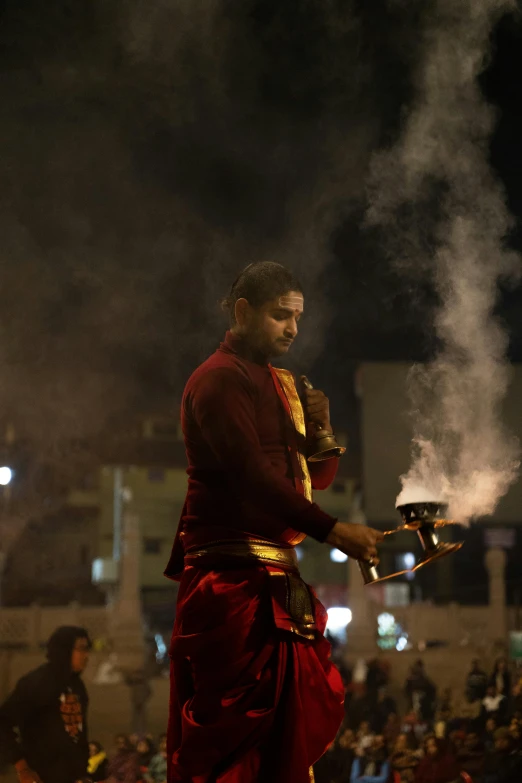 a man performing a ceremony at night with other people watching