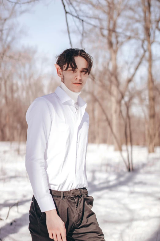 a man in a shirt and black pants is standing in the snow