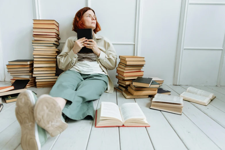 a woman sits on the floor surrounded by many books