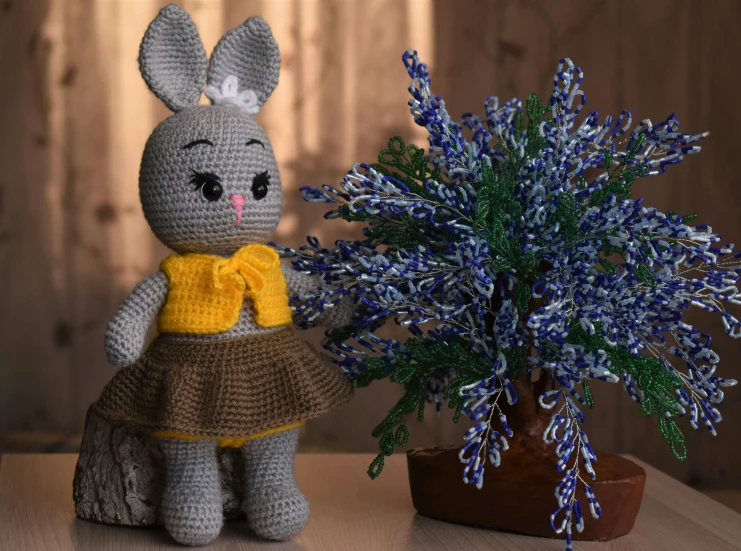 a crocheted bunny doll next to a small potted plant