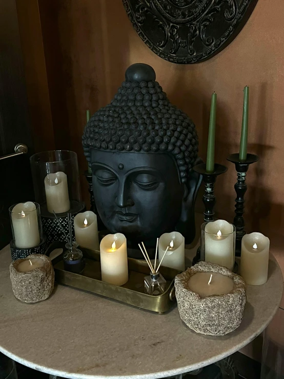 the buddha statue has a tray with candles near it