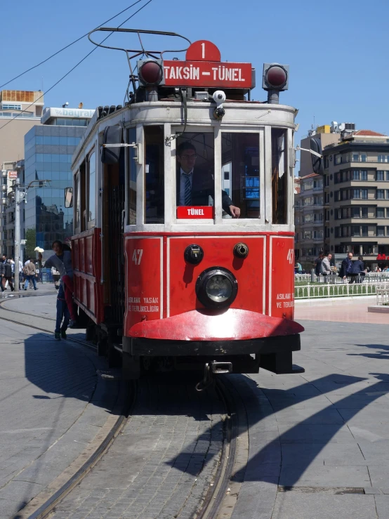 an old red trolley on tracks near buildings