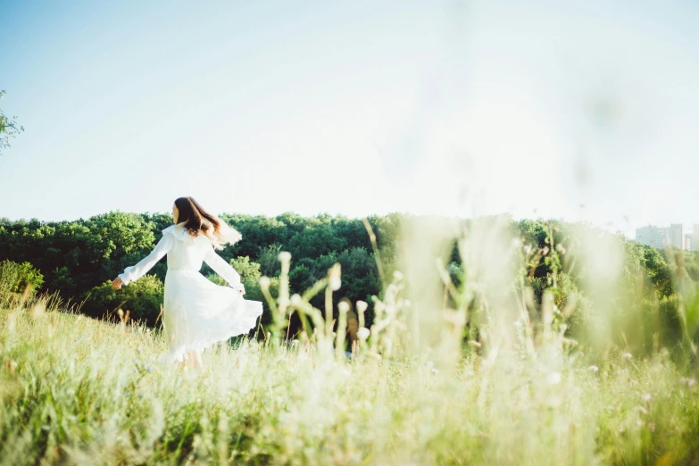 a woman in a white dress walks through tall grass