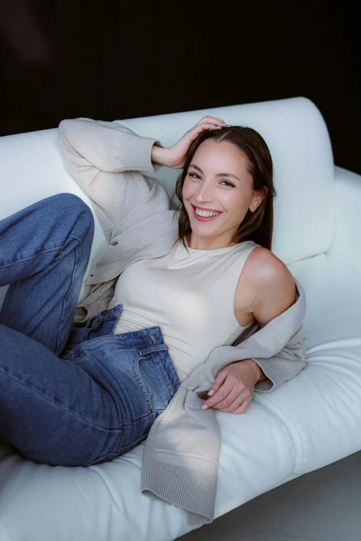 a beautiful woman laying on top of a white chair