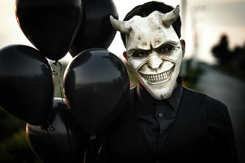 a person dressed in a mask holding balloons