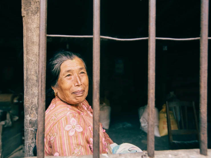 a woman standing behind bars in front of her home