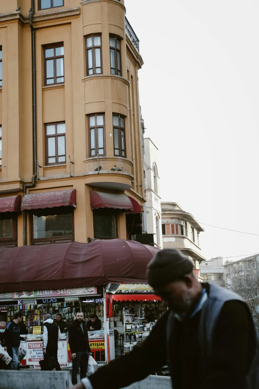 two men on a city street near a building with red awnings