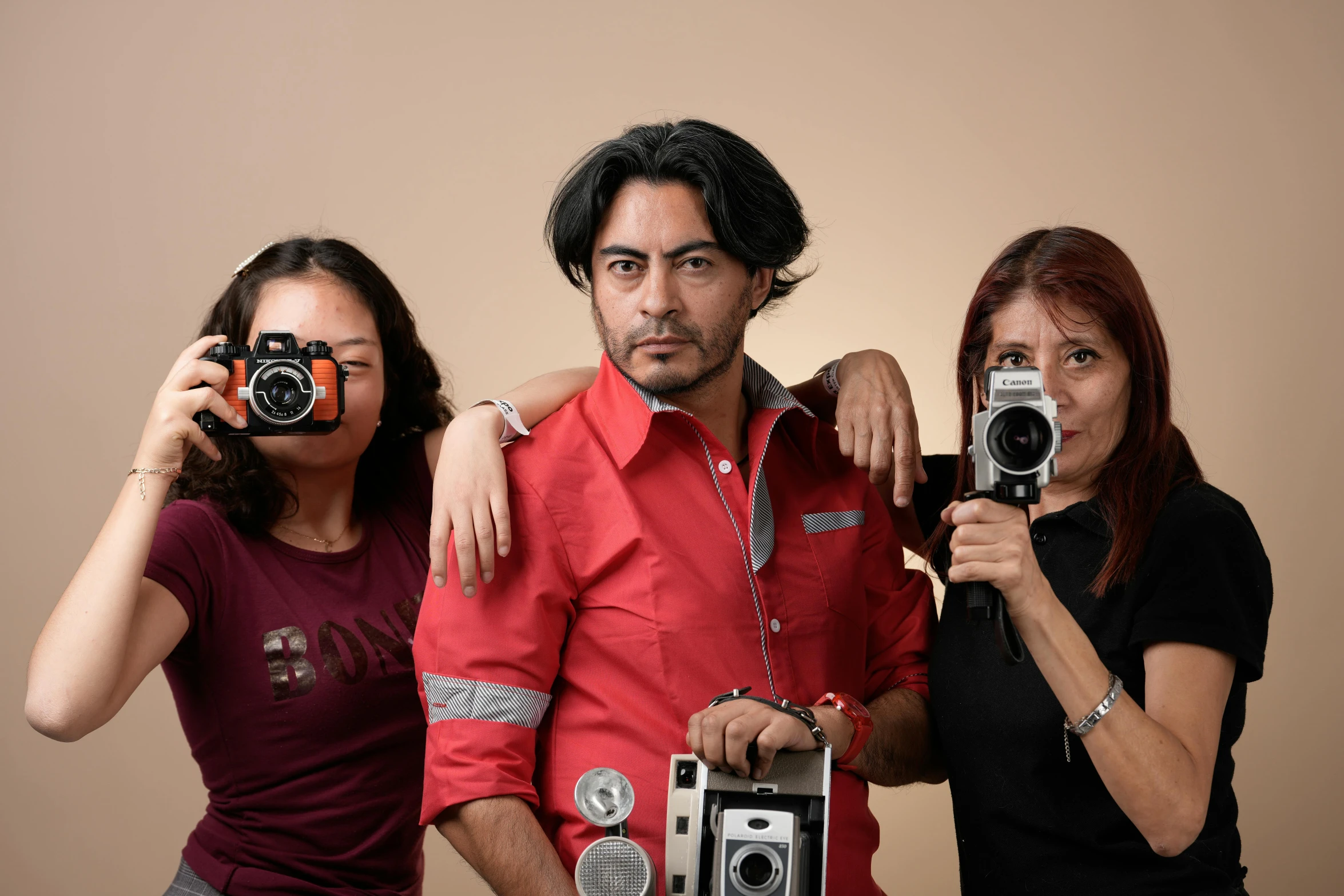 a couple holding up two old cameras and posing with one another