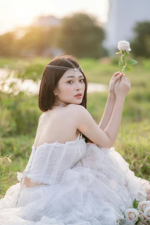 the girl in a dress with flowers sits on a grass field